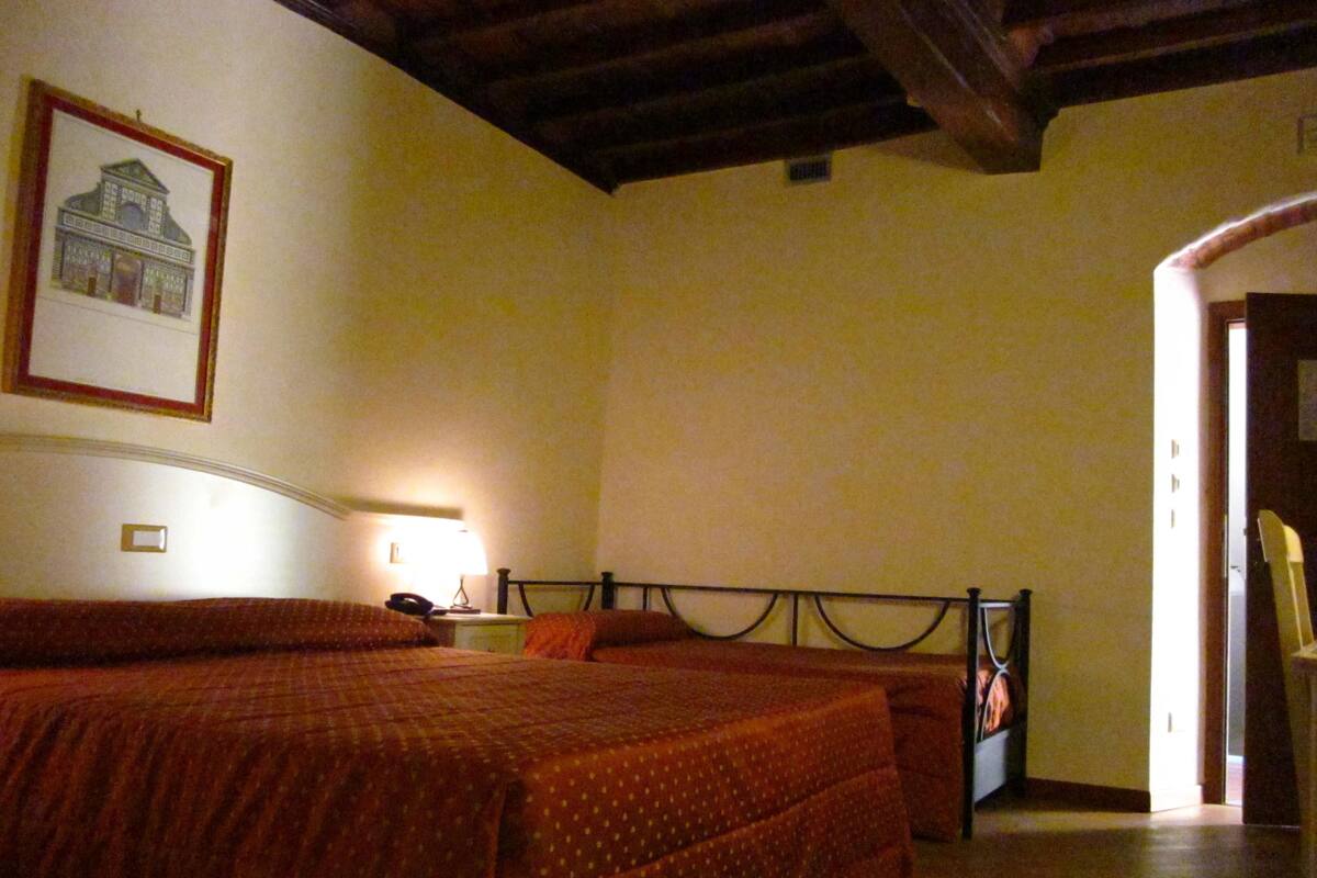 A bedroom with a bed, a nightstand, a lamp, and a framed picture on the wall.