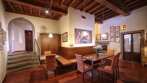 A dining area with a wooden table, chairs, and a bench. There is a staircase leading to another room, and a door with a window. - Hotel Villa S Michele (Carmignano)
