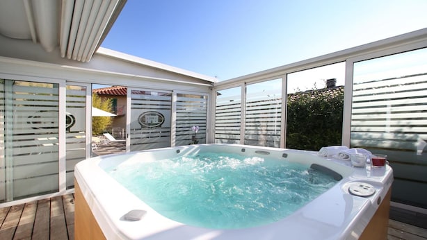 A hot tub on a wooden deck with large windows and a view of the sky. - Hotel Villa S Michele (Carmignano)
