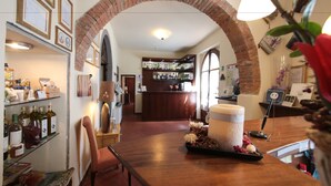 A bar area with a brick archway, shelves with bottles, and a counter with a large container and flowers. - Hotel Villa S Michele (Carmignano)