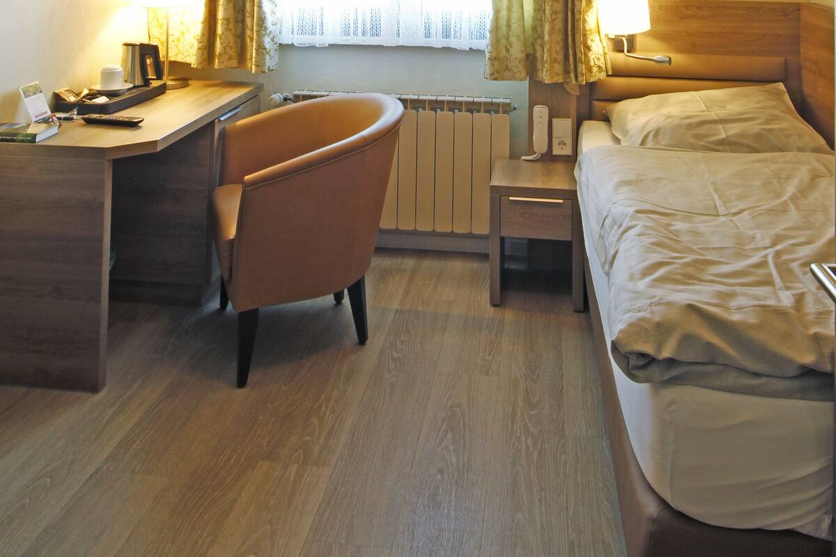 Une chambre d’hôtel équipée d’un bureau, d’une chaise, d’un lit et d’une fenêtre avec des rideaux.