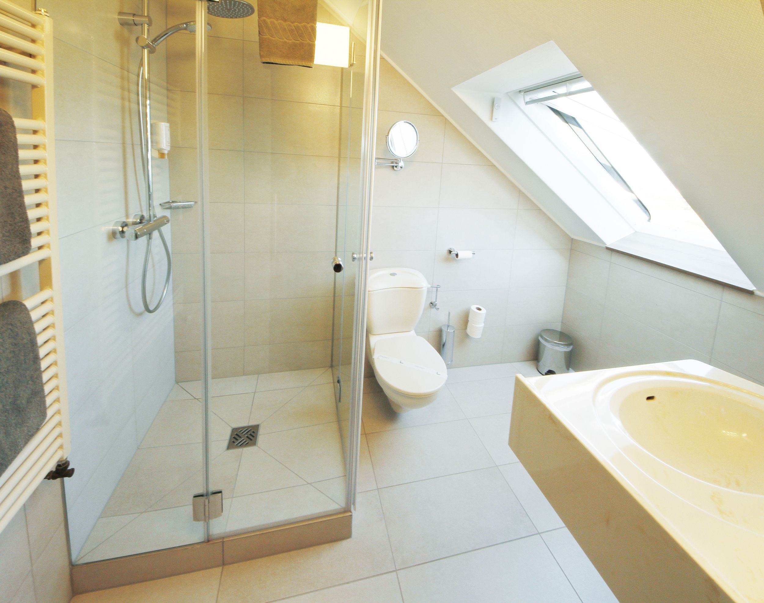 A modern bathroom with a glass-enclosed shower, a toilet, and a bathtub.