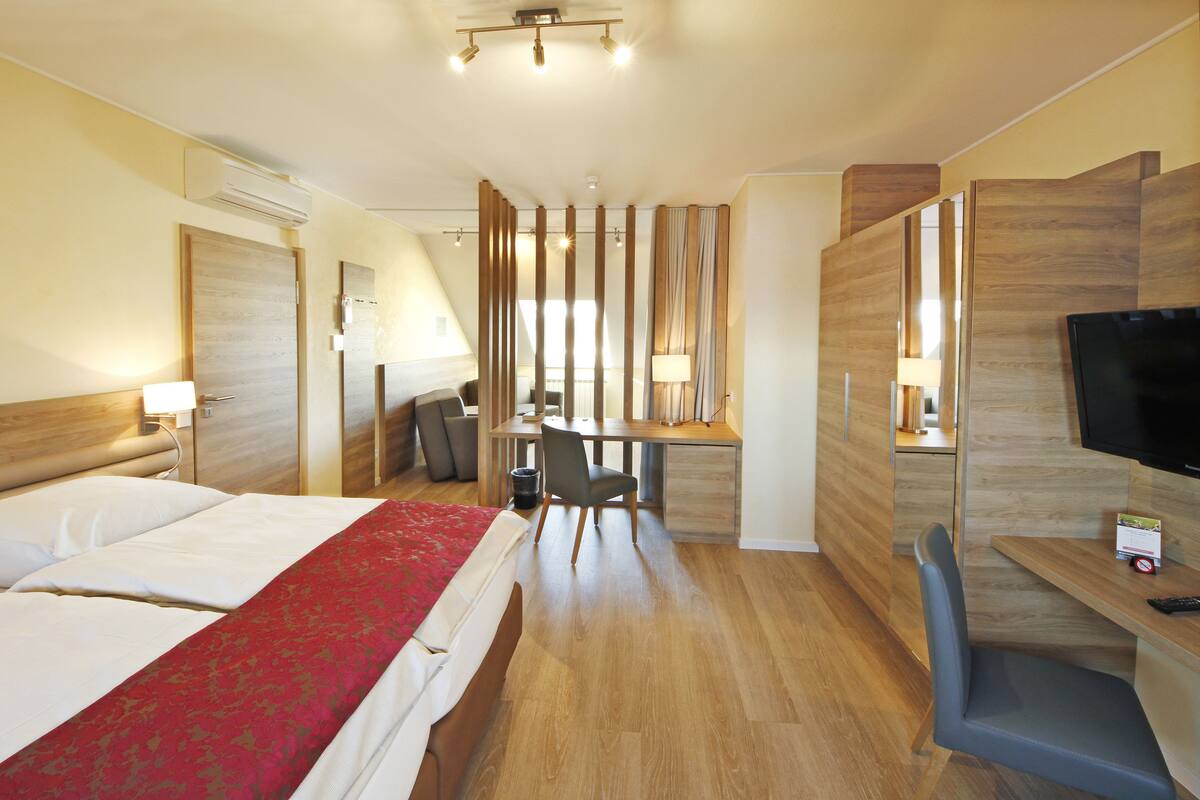 Une chambre d’hôtel équipée d’un lit, d’un bureau, d’une chaise, d  ’une télévision et d’une petite table avec une télécommande.