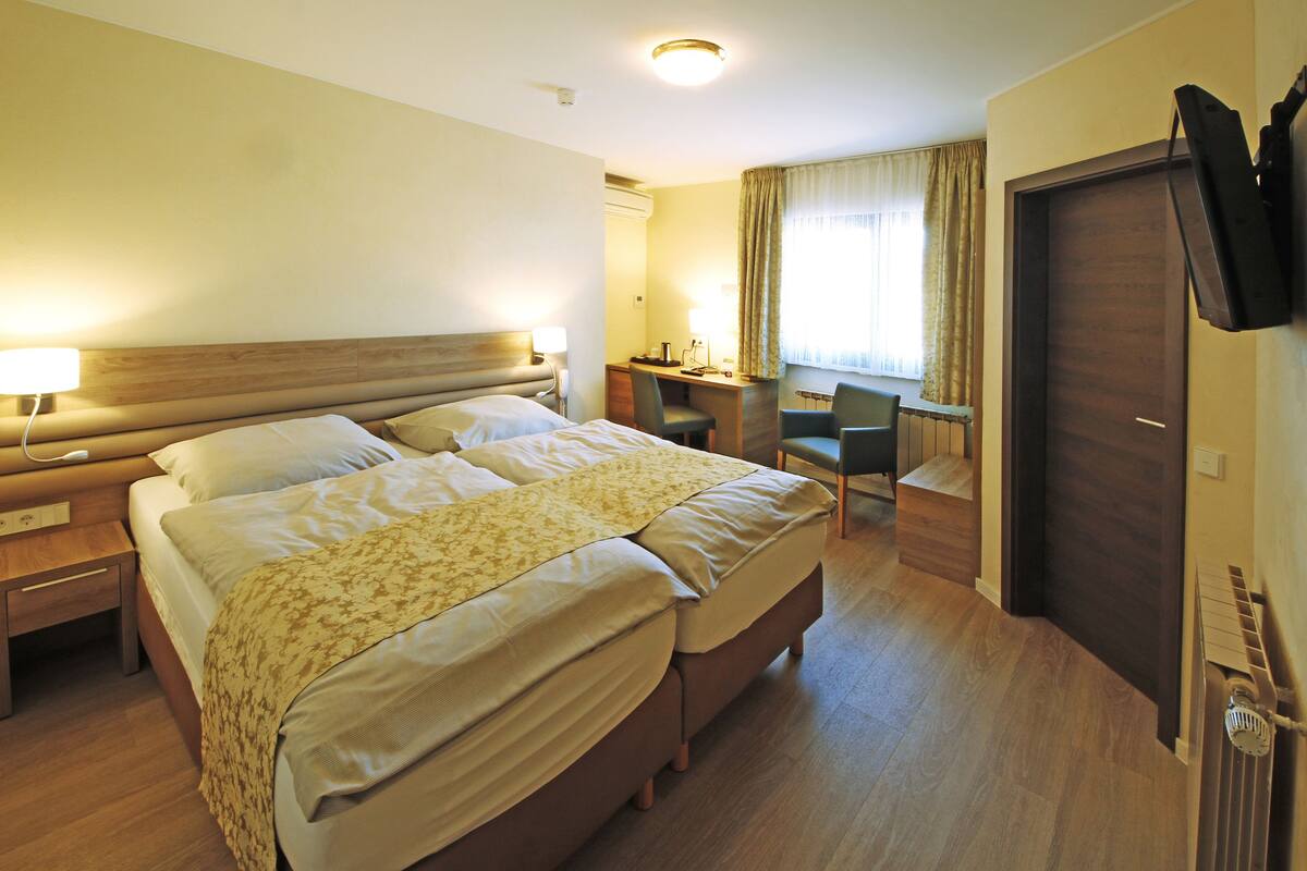 Une chambre d’hôtel avec un lit double, un bureau, une chaise, une télévision et une armoire.