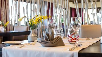 Una mesa de comedor adornada con un florero de flores amarillas, copas de vino y cubiertos.