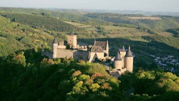 A medieval castle surrounded by lush green hills and forests.