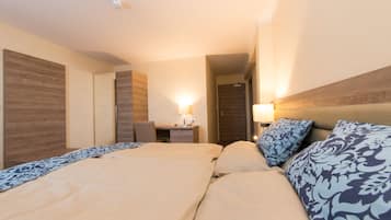 A hotel room with a large bed, a desk, and a wardrobe.