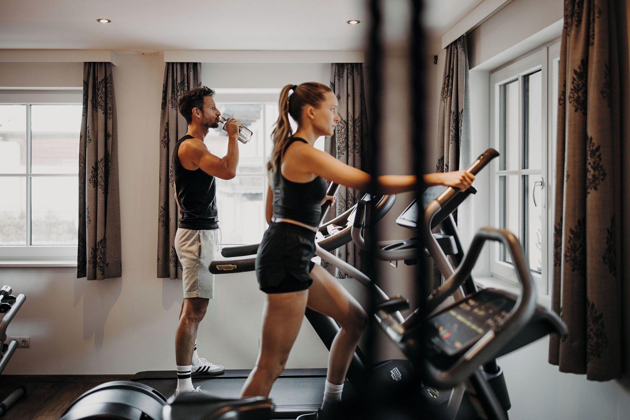 Ein Fitnessraum mit Laufbändern und einer Person, die ein Hanteltrainer benutzt.