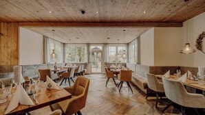 Tilava ravintola, jossa on puulattia ja korkea katto. Pöydät on katettu valkoisilla lautasliinoilla ja lasilla.