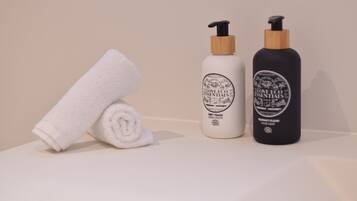 Une serviette blanche et deux flacons de crème pour les mains sont posés sur une surface blanche.