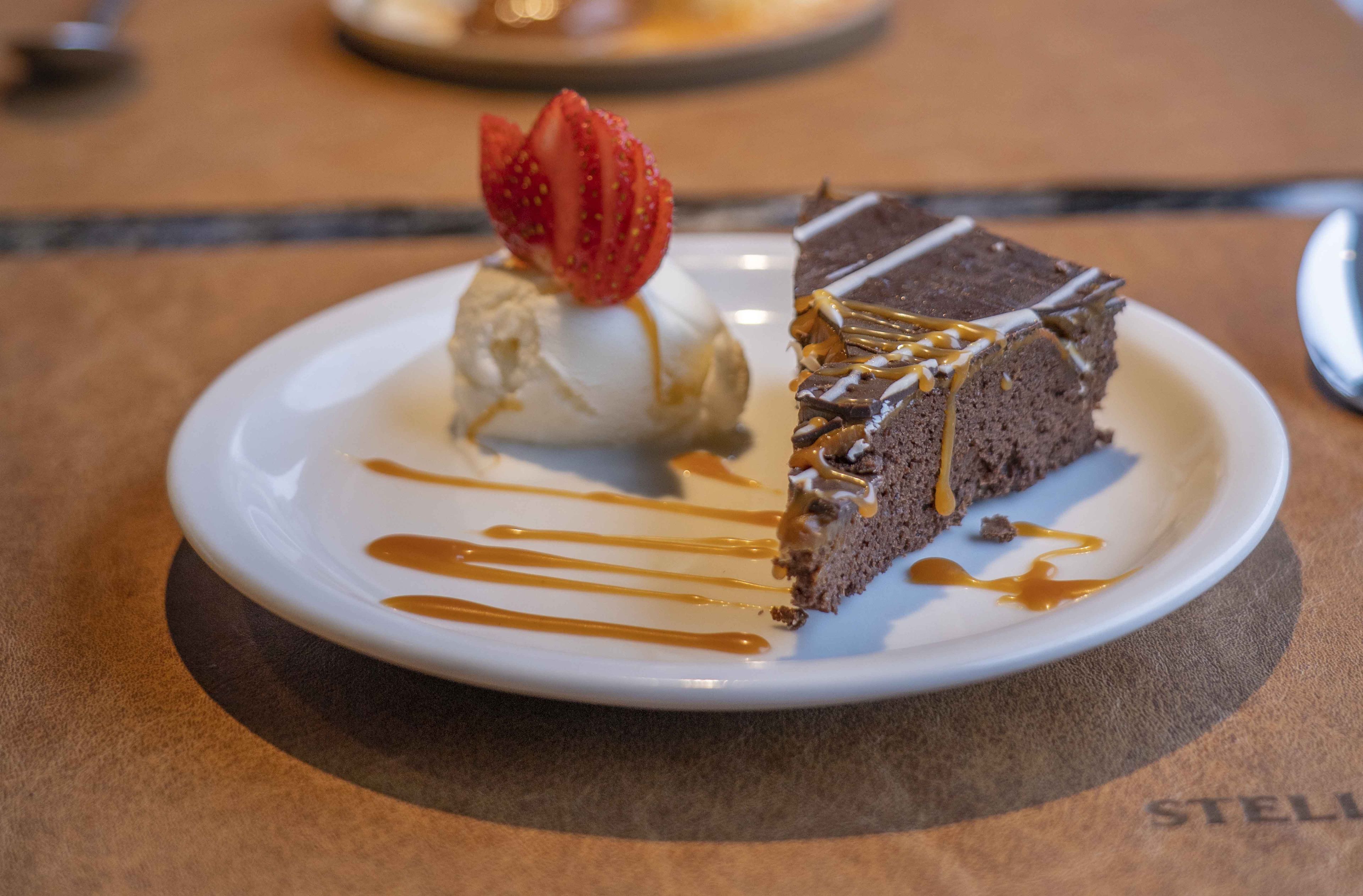 A dessert plate with a slice of chocolate cake, a scoop of vanilla ice cream, and a strawberry garnish.