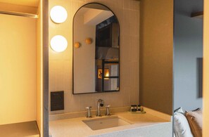 Un baño con un espejo grande, un lavamanos y dos luces redondas en la pared.