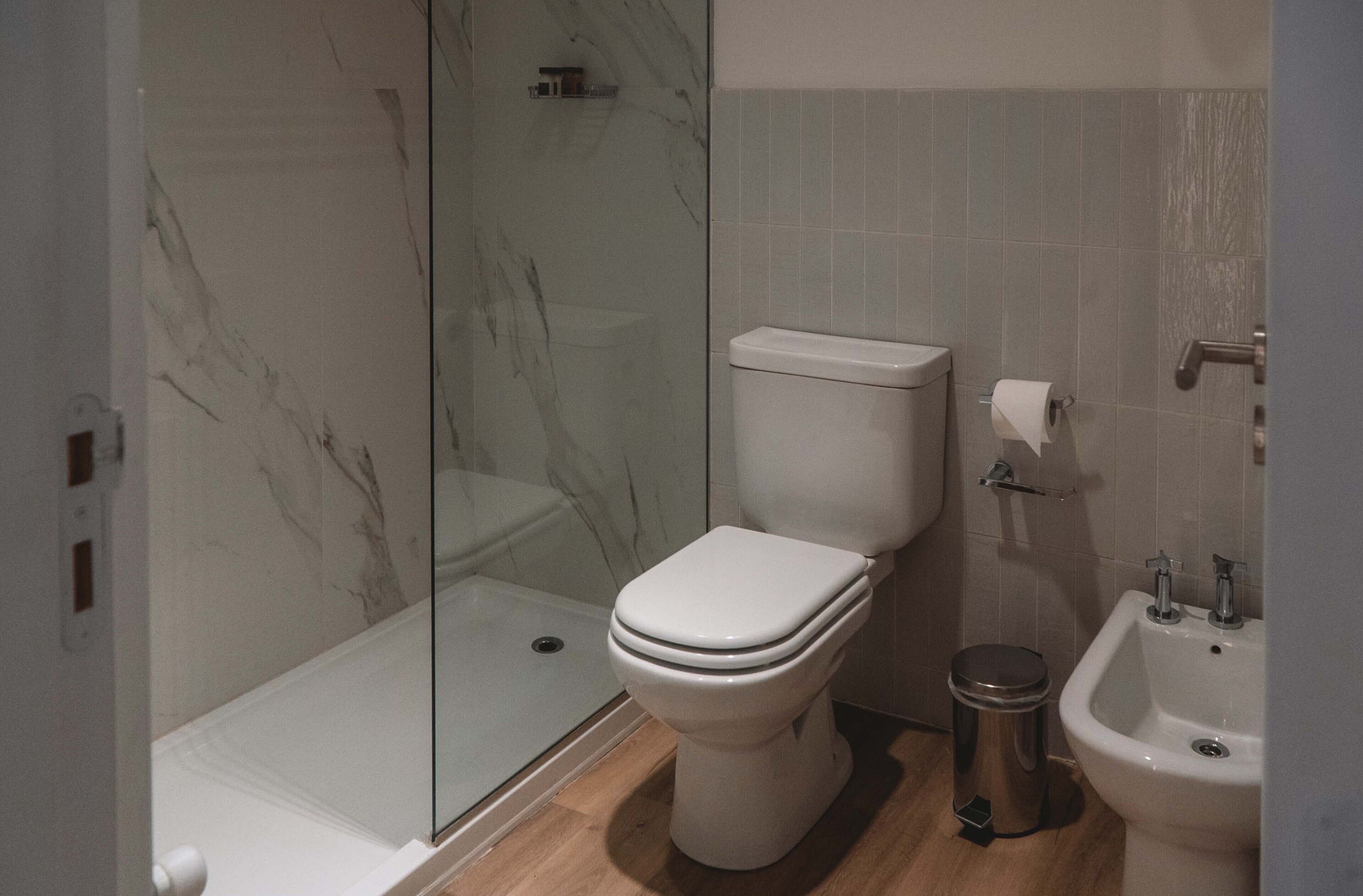 A modern bathroom with a toilet, bidet, and glass shower enclosure.