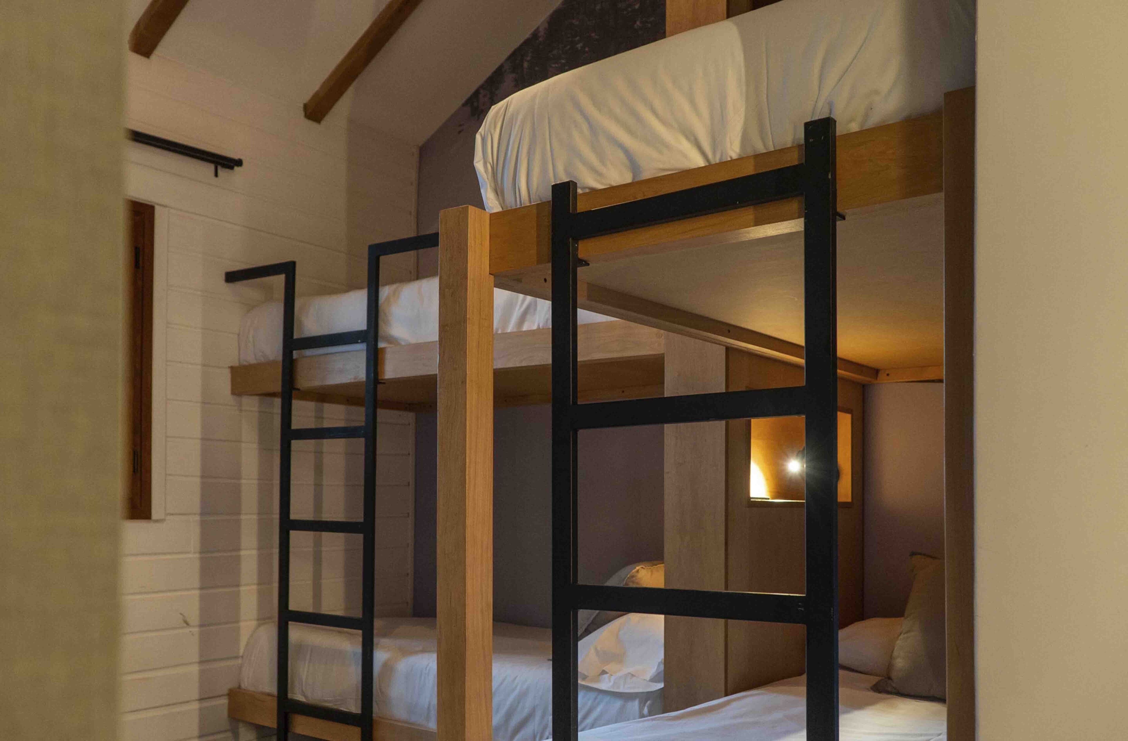 Dormitorio con literas de madera y ropa de cama blanca.