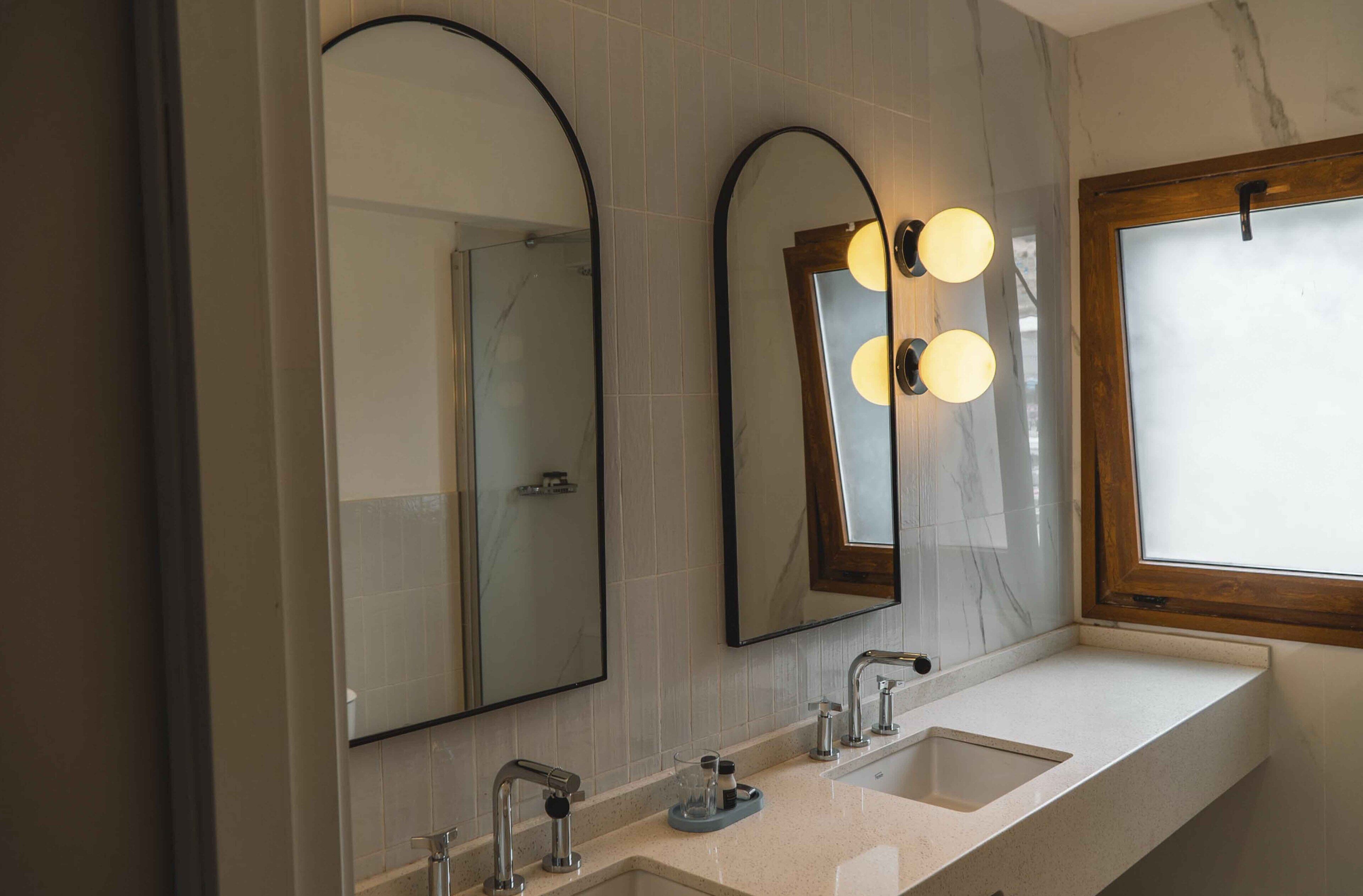 A bathroom with two sinks, a mirror, and a window.