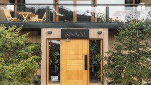 A building with a wooden door labeled "KNAPP" and a balcony with outdoor seating. - Refugio Knapp (San Carlos de Bariloche)