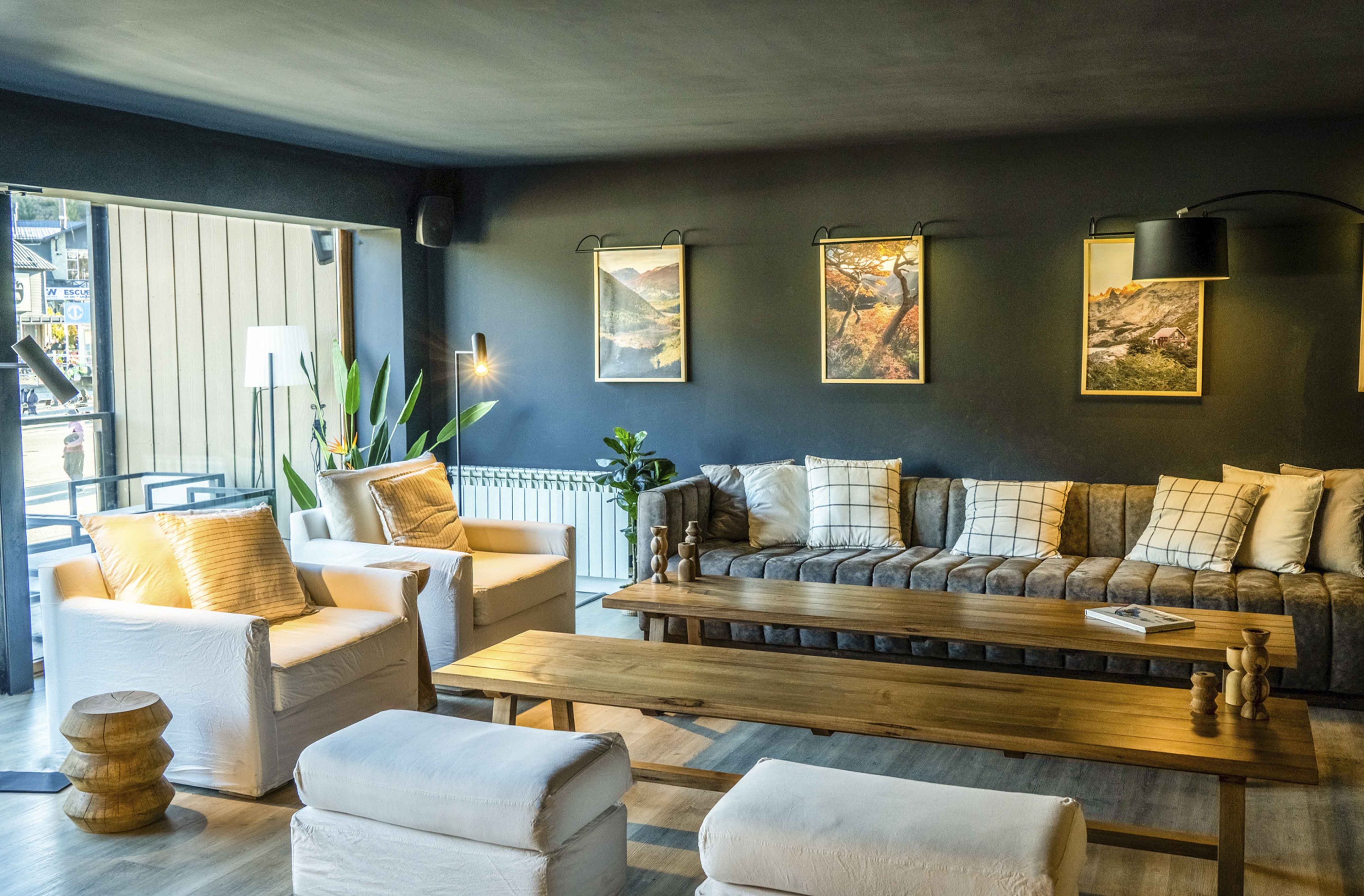 A modern living room with a sofa, armchairs, and a coffee table. There are framed pictures on the wall and a plant on the floor.