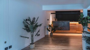 Un moderno vestíbulo de hotel con piso de madera, paredes blancas y plantas en macetas.