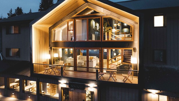 A two-story wooden cabin with a balcony, large windows, and a staircase leading to the upper floor. - Refugio Knapp (San Carlos de Bariloche)