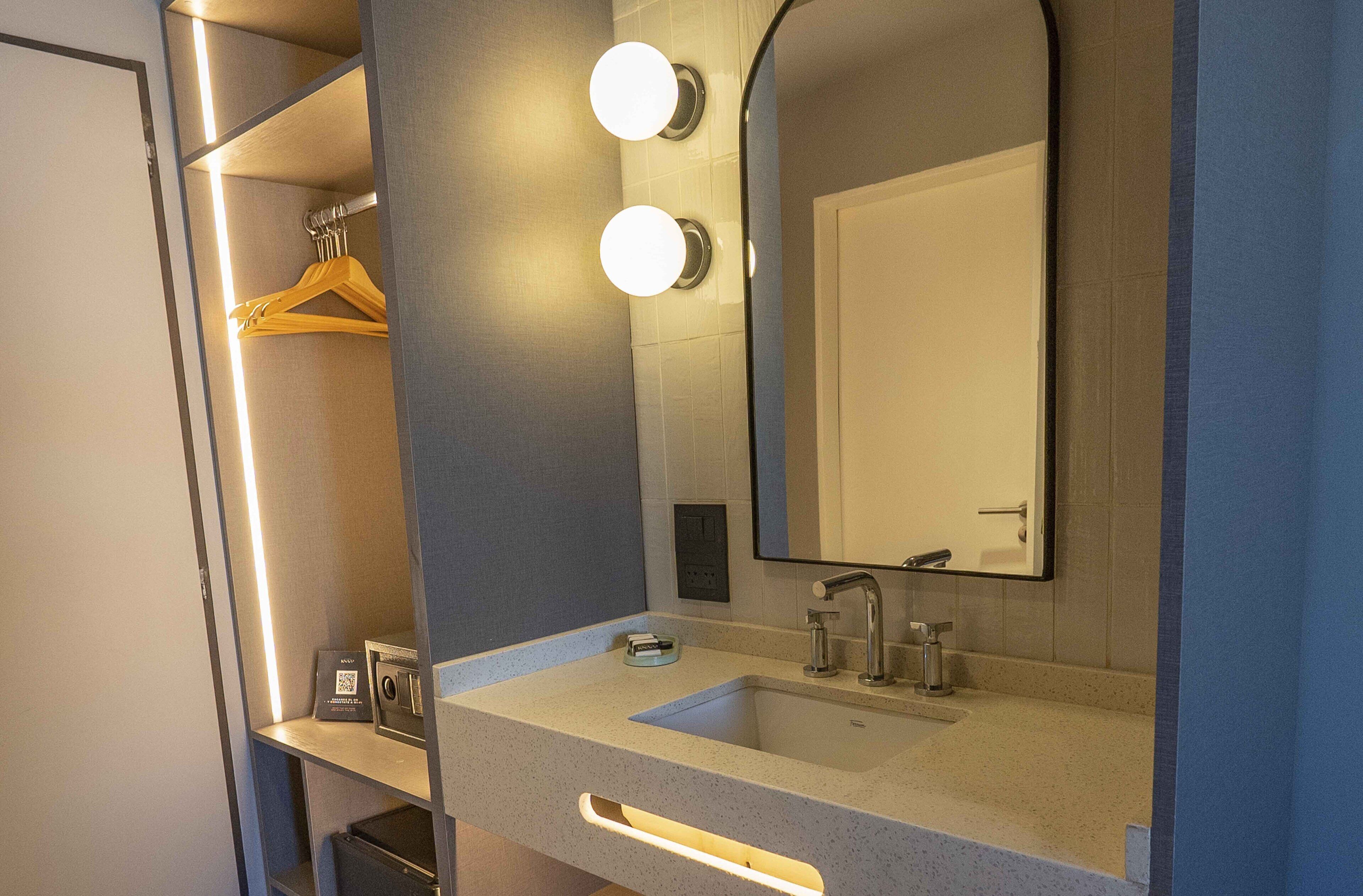 A bathroom with a large mirror, a sink, and a towel rack.