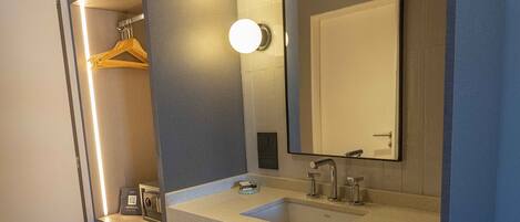 A bathroom with a large mirror, a sink, and a towel rack.