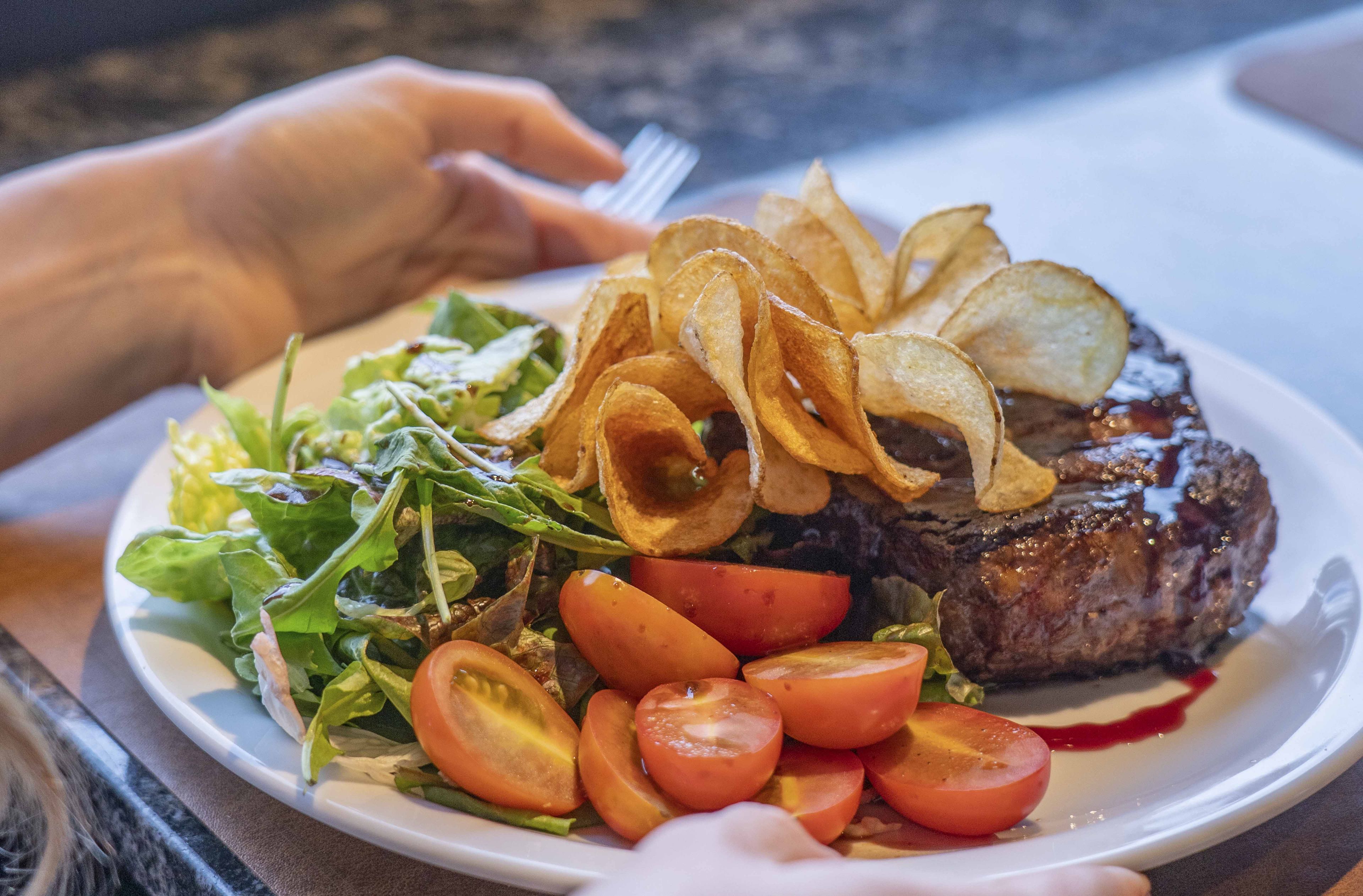 Une assiette avec un steak, des tomates cerises et une salade en accompagnement.
