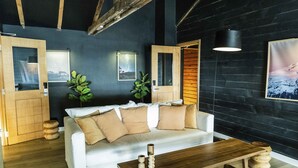 A modern living room with a white sofa, wooden coffee table, and a dark wall with framed pictures. - Refugio Knapp (San Carlos de Bariloche)