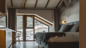 Un dormitorio con un ventanal grande, una cama y vistas a un paisaje nevado.