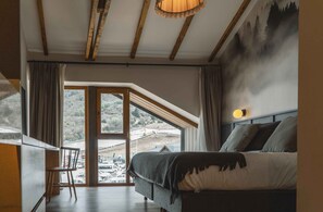 A bedroom with a large window, a bed, and a view of a snowy landscape.