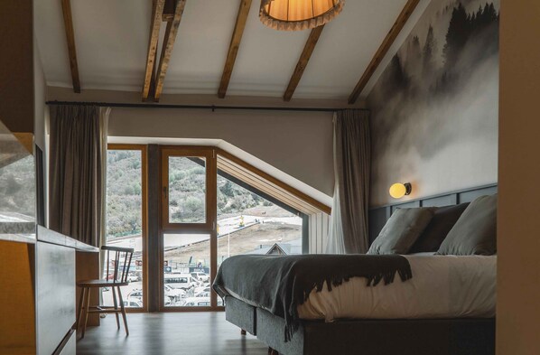 Un dormitorio con un ventanal grande, una cama y vistas a un paisaje nevado.