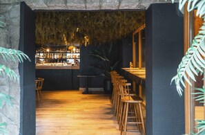 A bar area with wooden stools and a counter, surrounded by dark walls and a hanging moss ceiling. - Refugio Knapp (San Carlos de Bariloche)