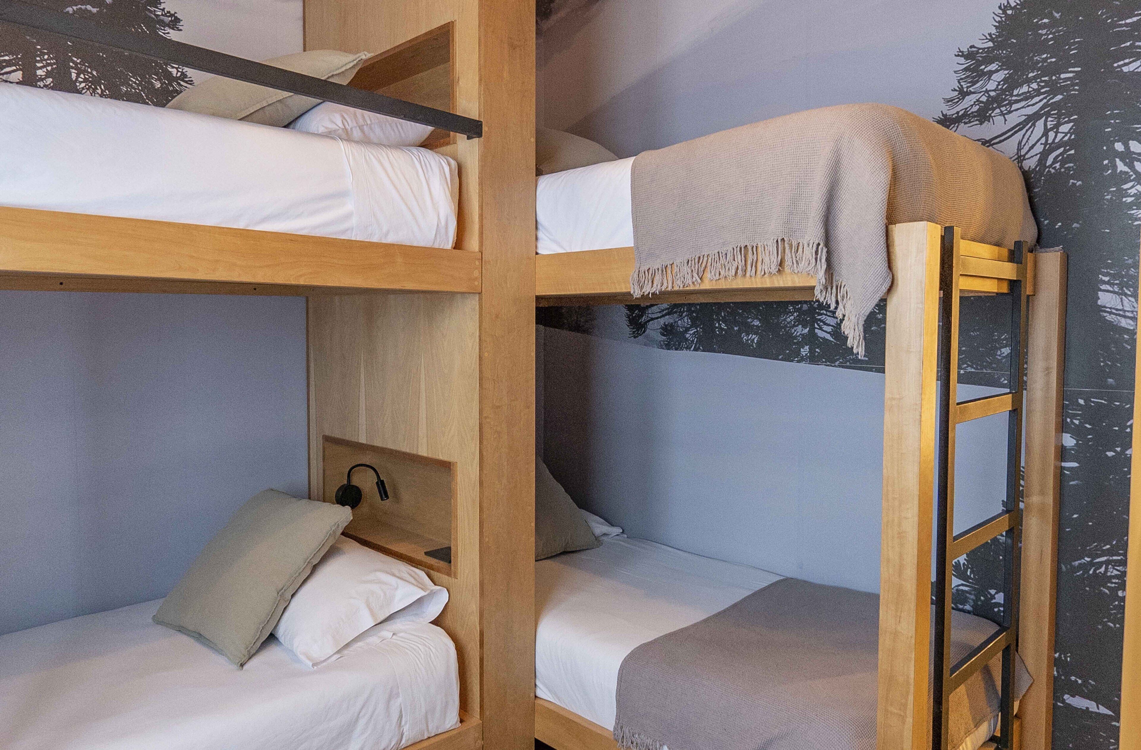 A bunk bed room with a wooden ladder, a headboard, and a wall mural.