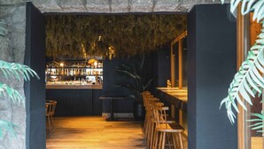 A bar area with wooden stools and a counter, surrounded by dark walls and a hanging moss ceiling. - Refugio Knapp (San Carlos de Bariloche)