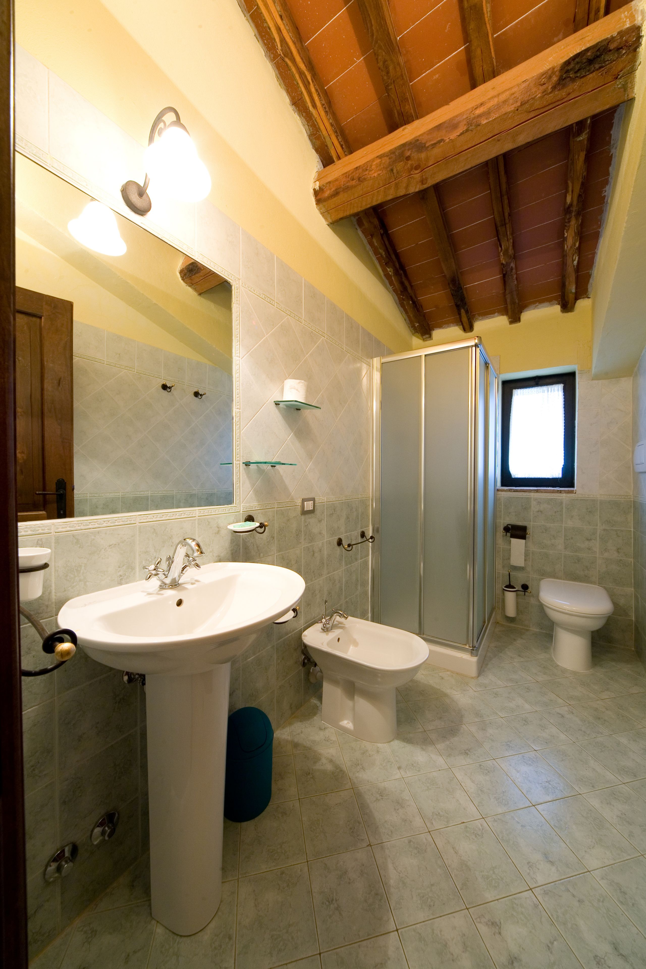 Een badkamer met een groot wastafel, toilet, douche en een raam.