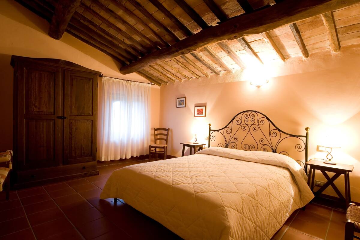 Een slaapkamer met een groot bed, een houten garderobe en een stoel.