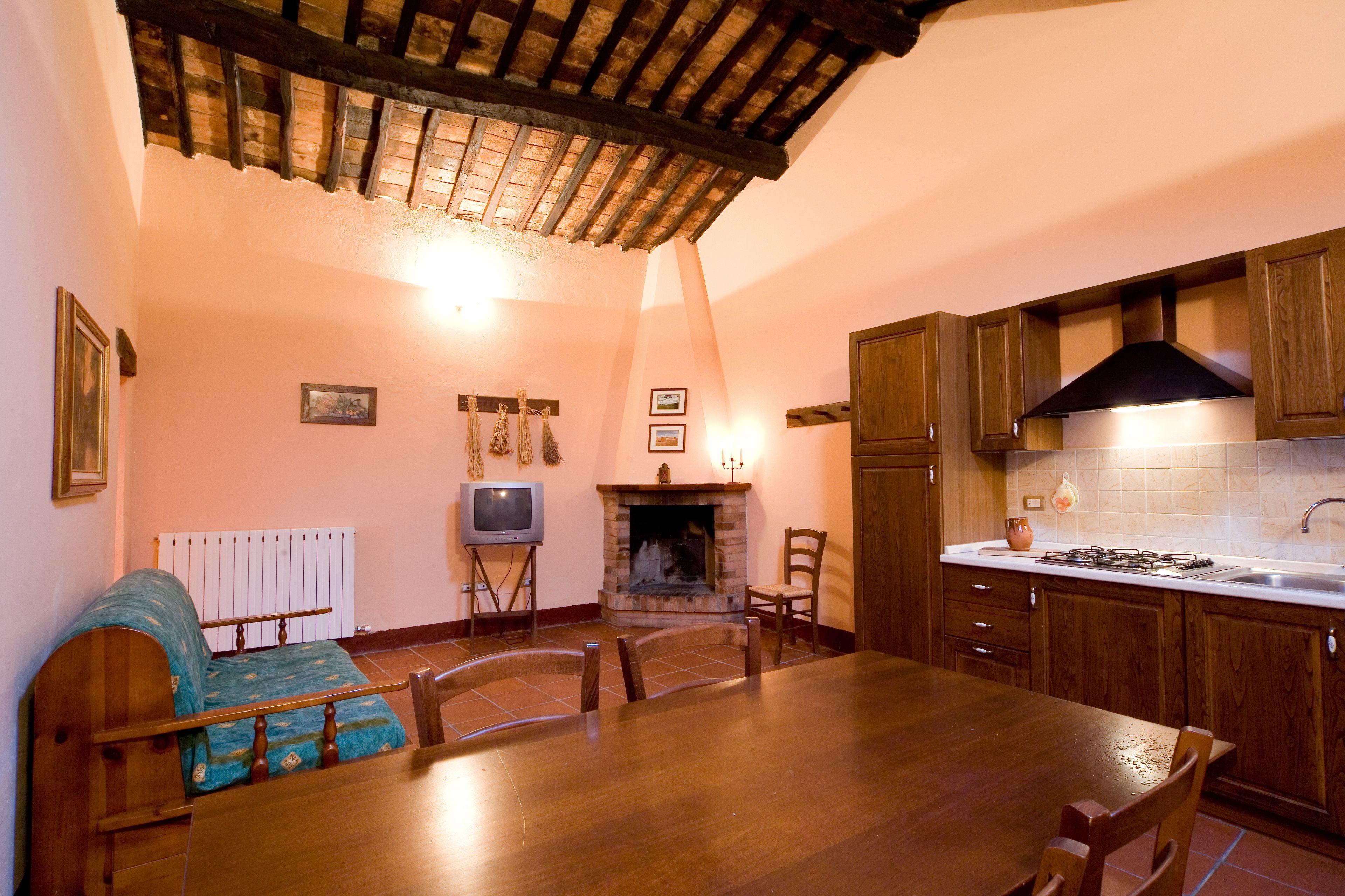 Una cocina acogedora con una mesa de comedor, sillas, una chimenea, armarios de madera y un salpicadero de azulejos.