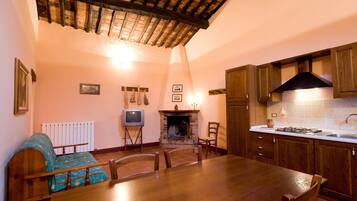 Una cocina acogedora con una mesa de comedor, sillas, una chimenea, armarios de madera y un salpicadero de azulejos.