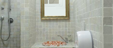 Un baño con ducha, inodoro, lavabo y un espejo enmarcado.