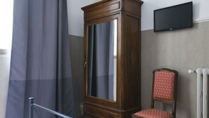 A room with a wooden wardrobe, a red upholstered chair, and a mounted flat-screen TV. - Loggia Fiorentina (Florence)