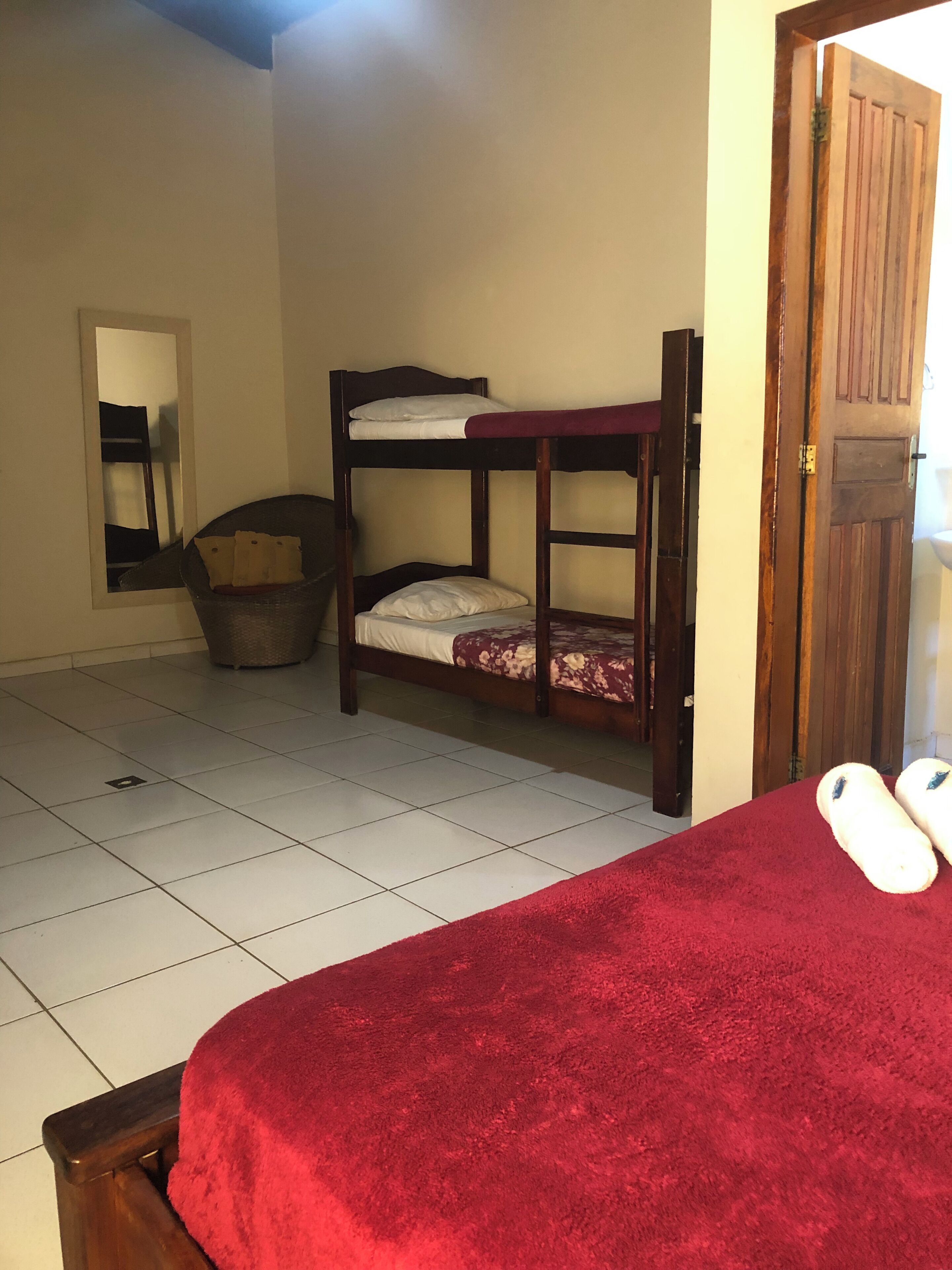 Ein Zimmer mit Etagenbetten, einem roten Teppich, einer Holztür und einem Fliesenboden.