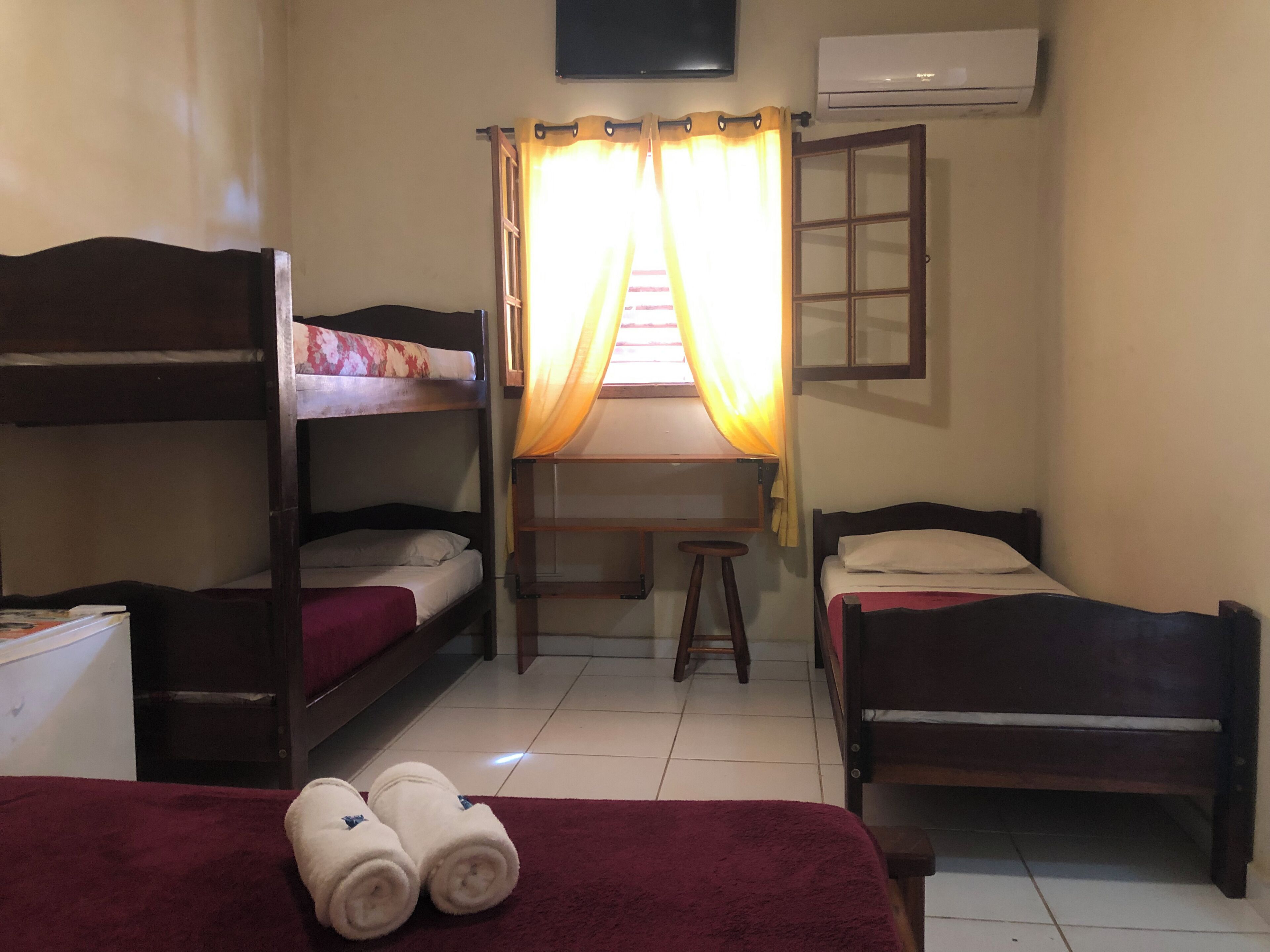 A dormitory room with bunk beds, a desk, a chair, and a TV.