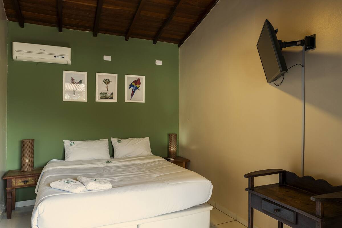 A hotel room with a bed, a nightstand, a lamp, and a wall-mounted TV.