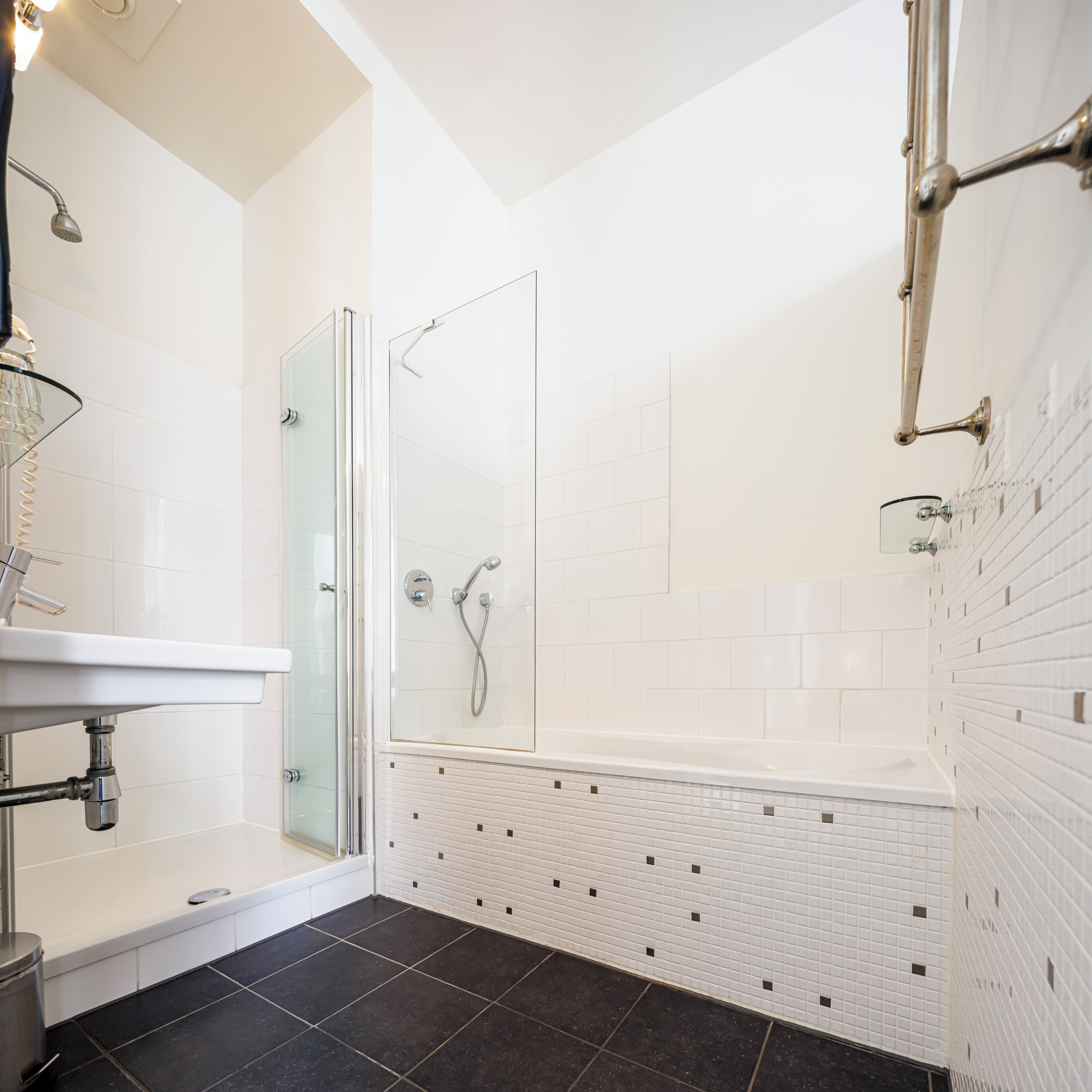 Un baño moderno con cabina de ducha de vidrio, un lavabo blanco y una bañera.