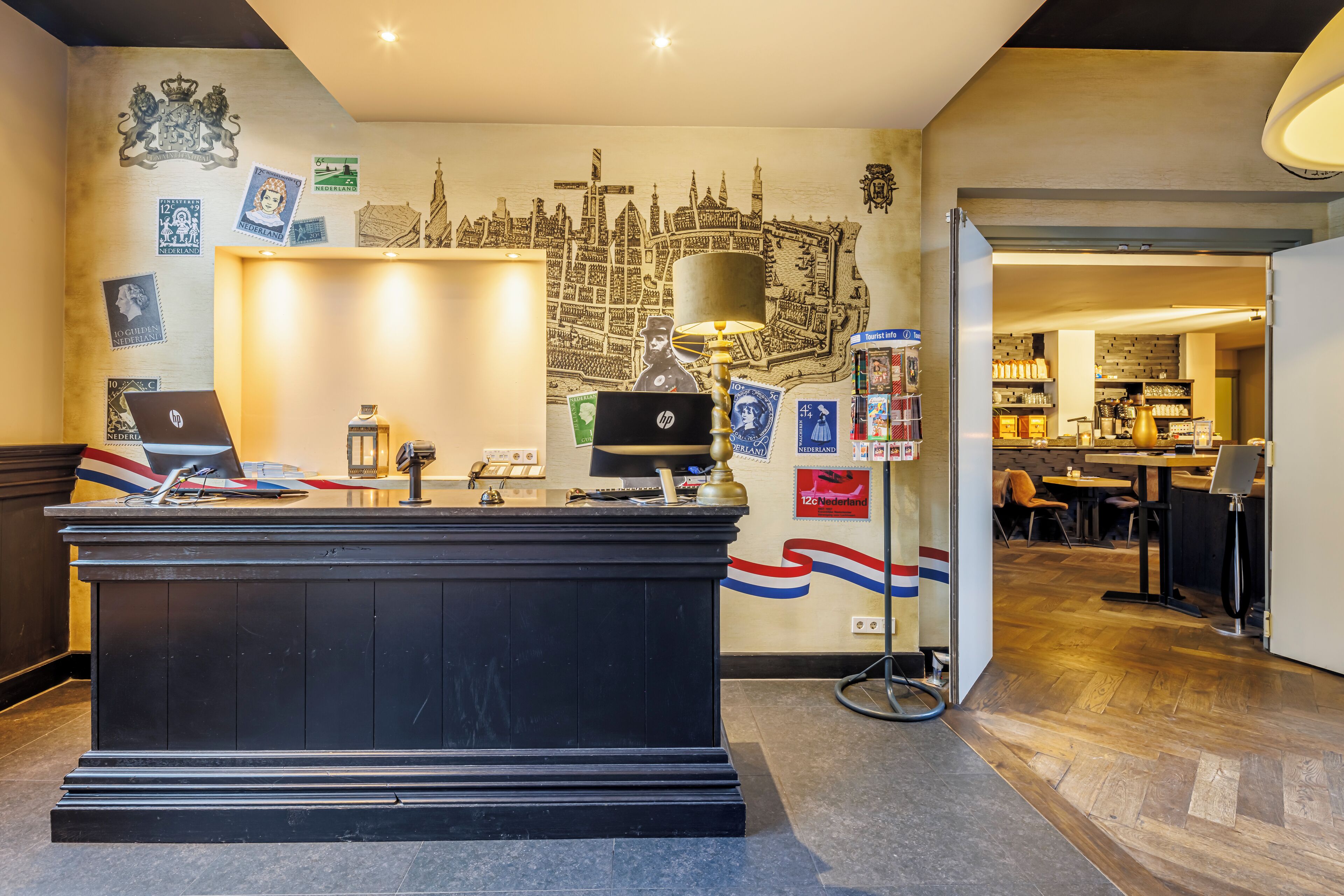 A reception desk with a laptop, a lamp, and various postcards.