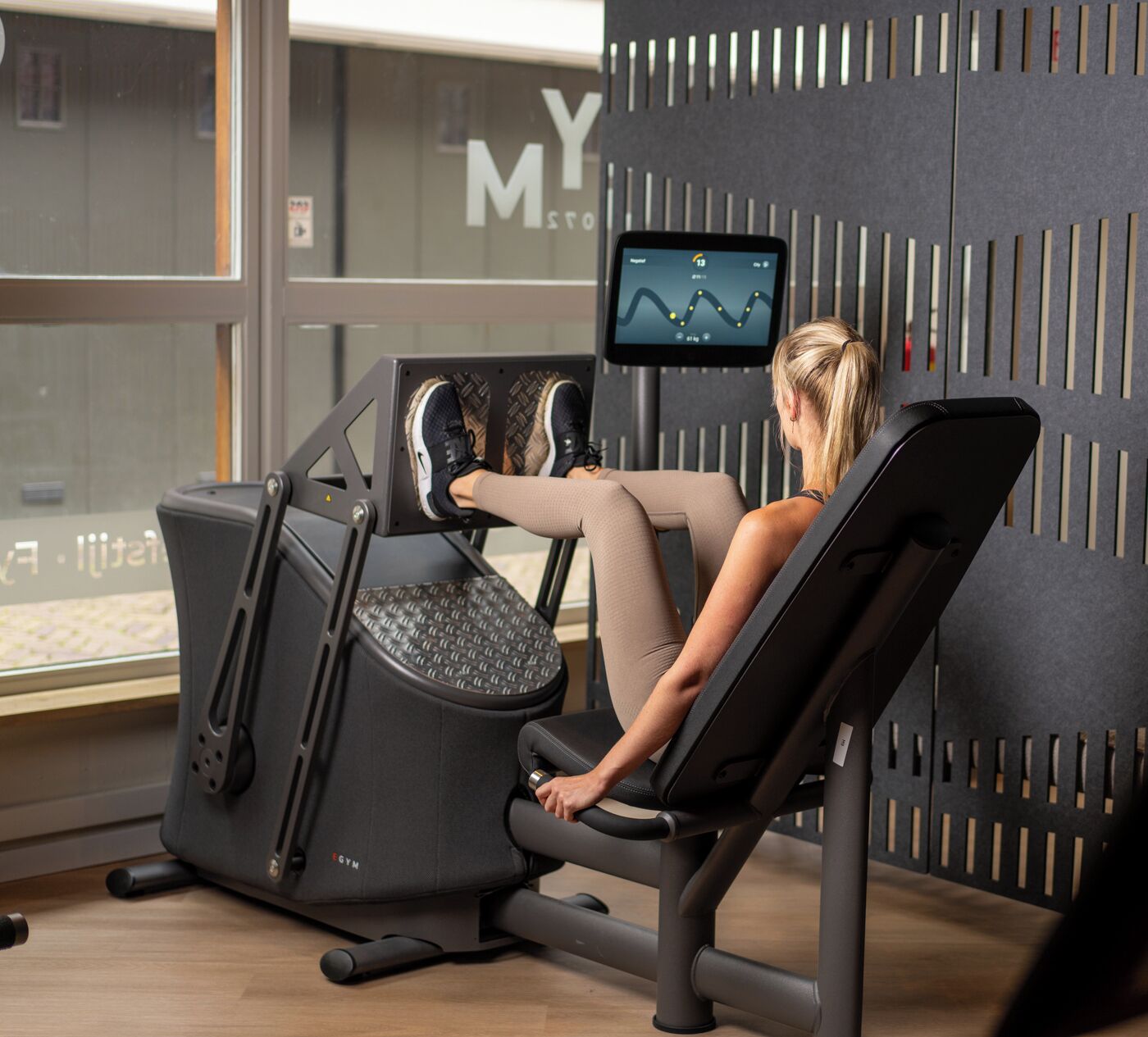 A person using a stationary bike in a gym with a digital display showing a graph.