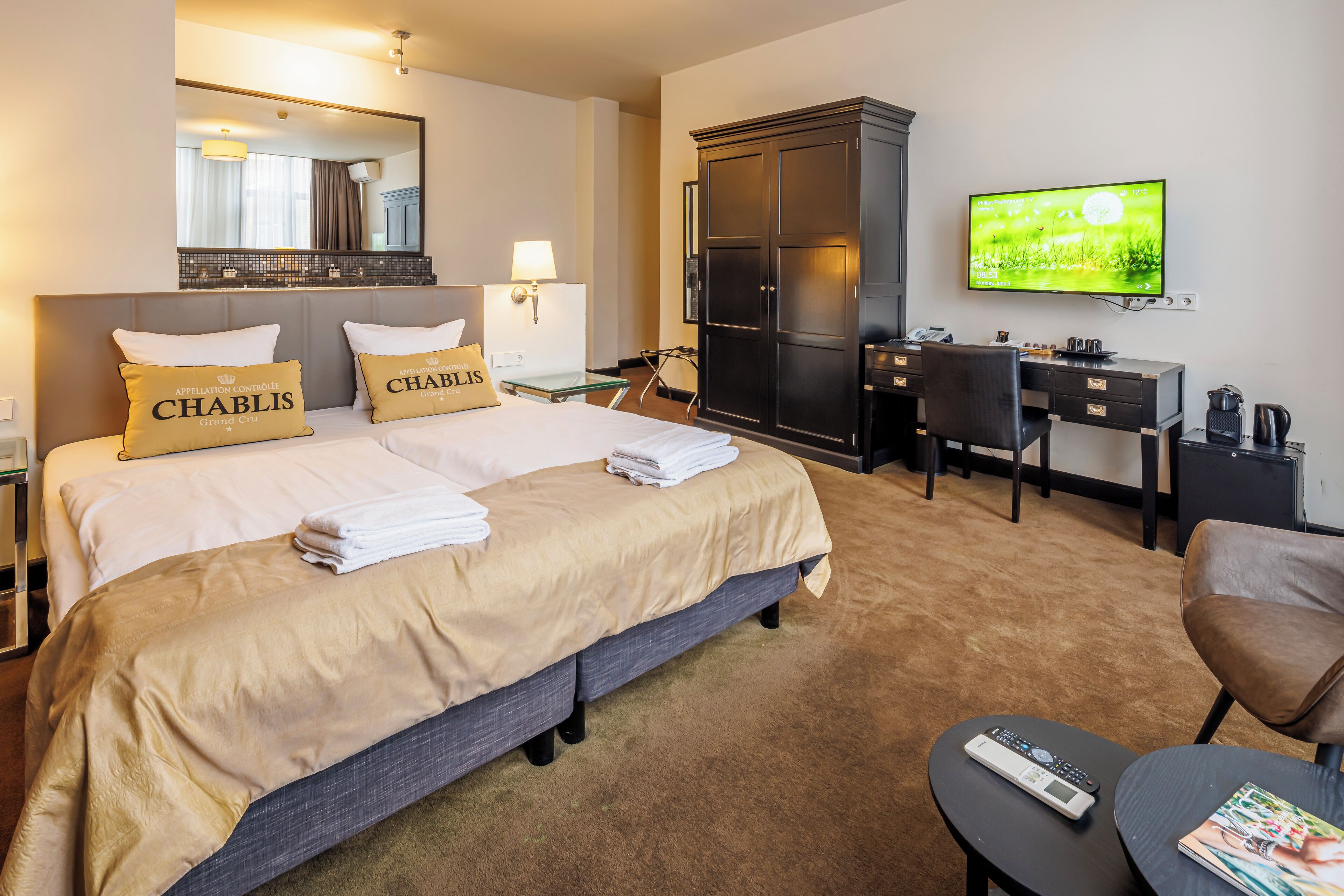Une chambre d’hôtel avec un grand lit, un bureau, une télévision et une armoire.