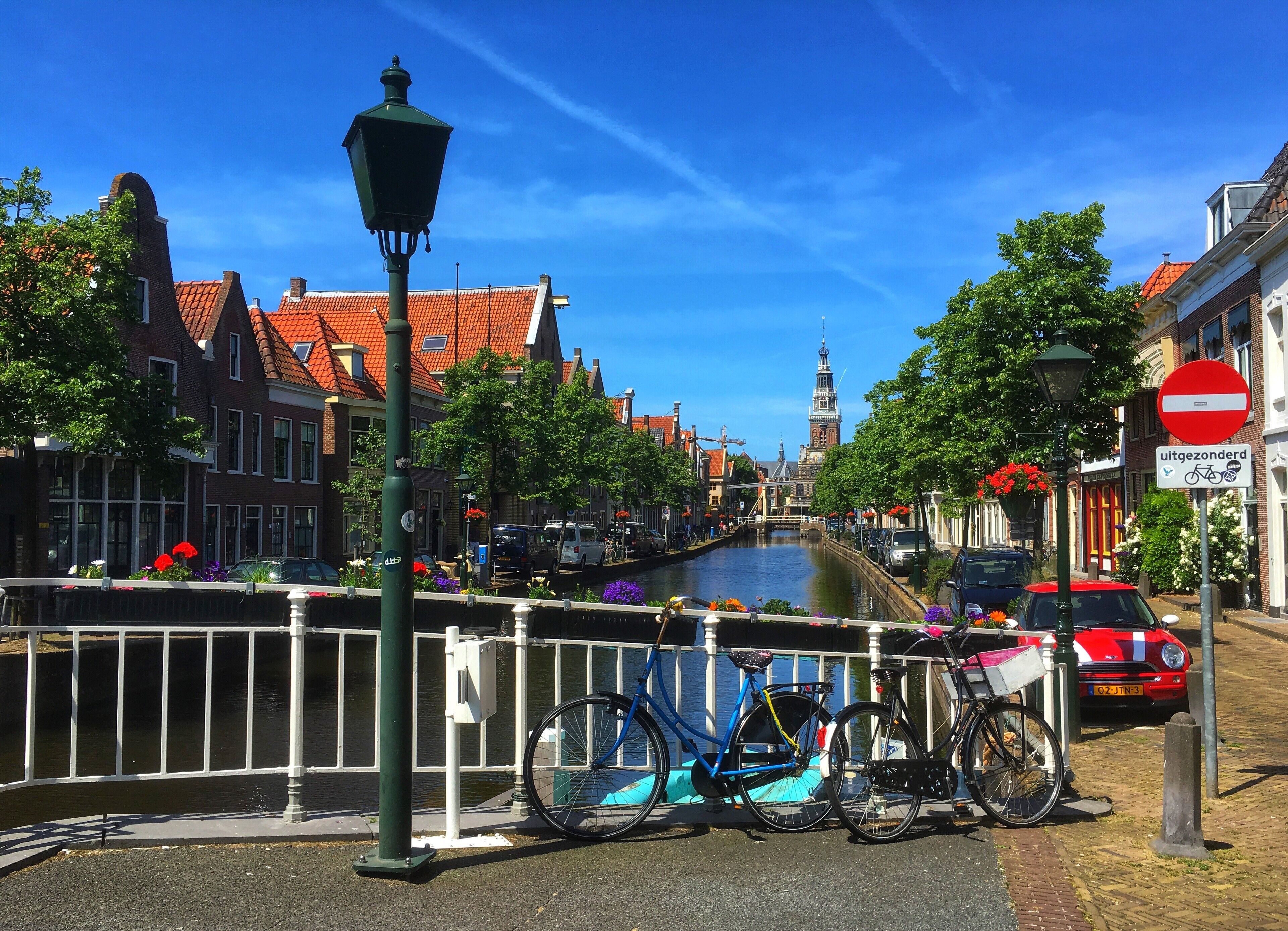 Ein Kanal mit einer Brücke, Gebäuden mit roten Dächern und einem Fahrrad am Kanal.