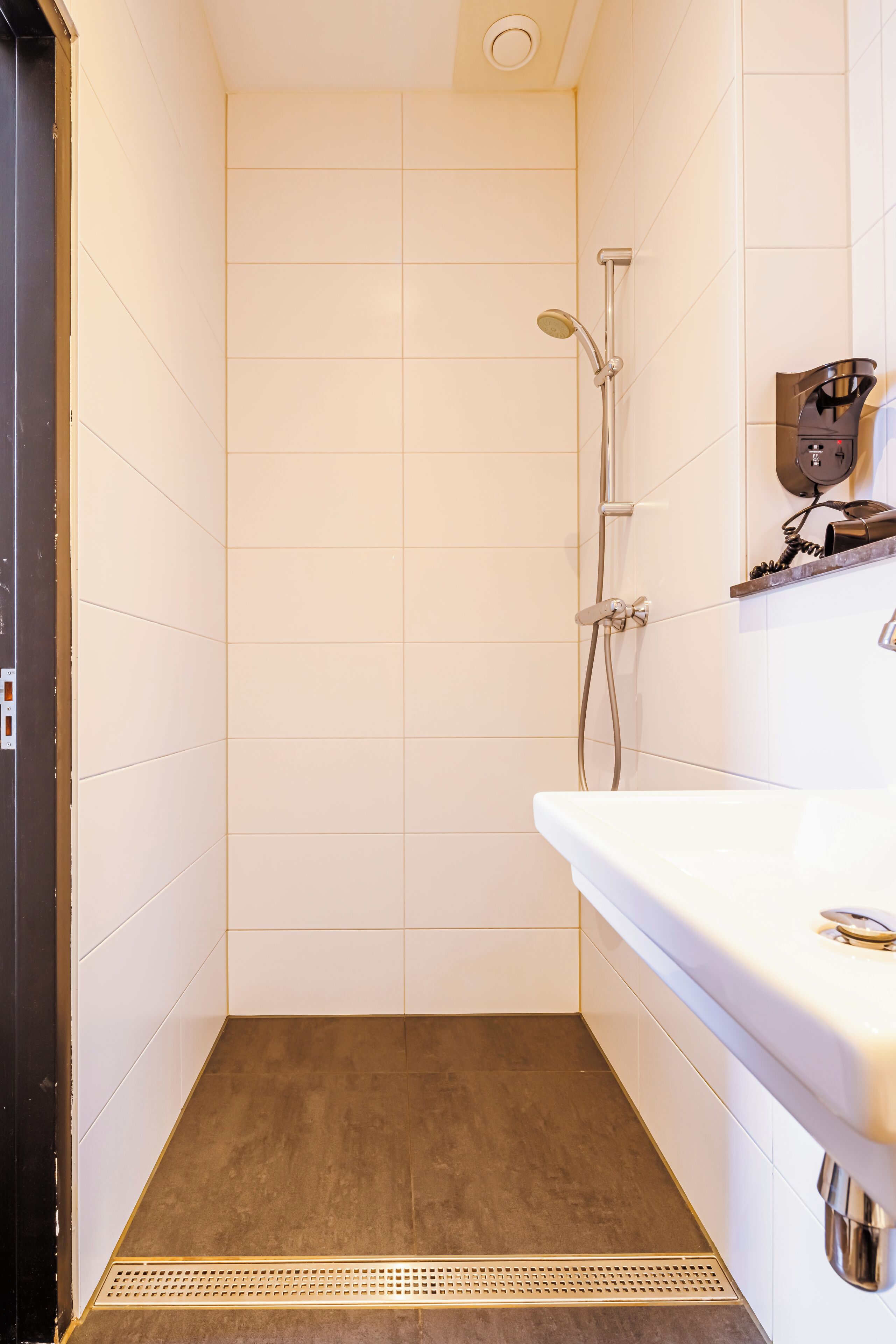 Une petite salle de bain moderne, équipée d’une douche, d’un lavabo et d’un miroir.