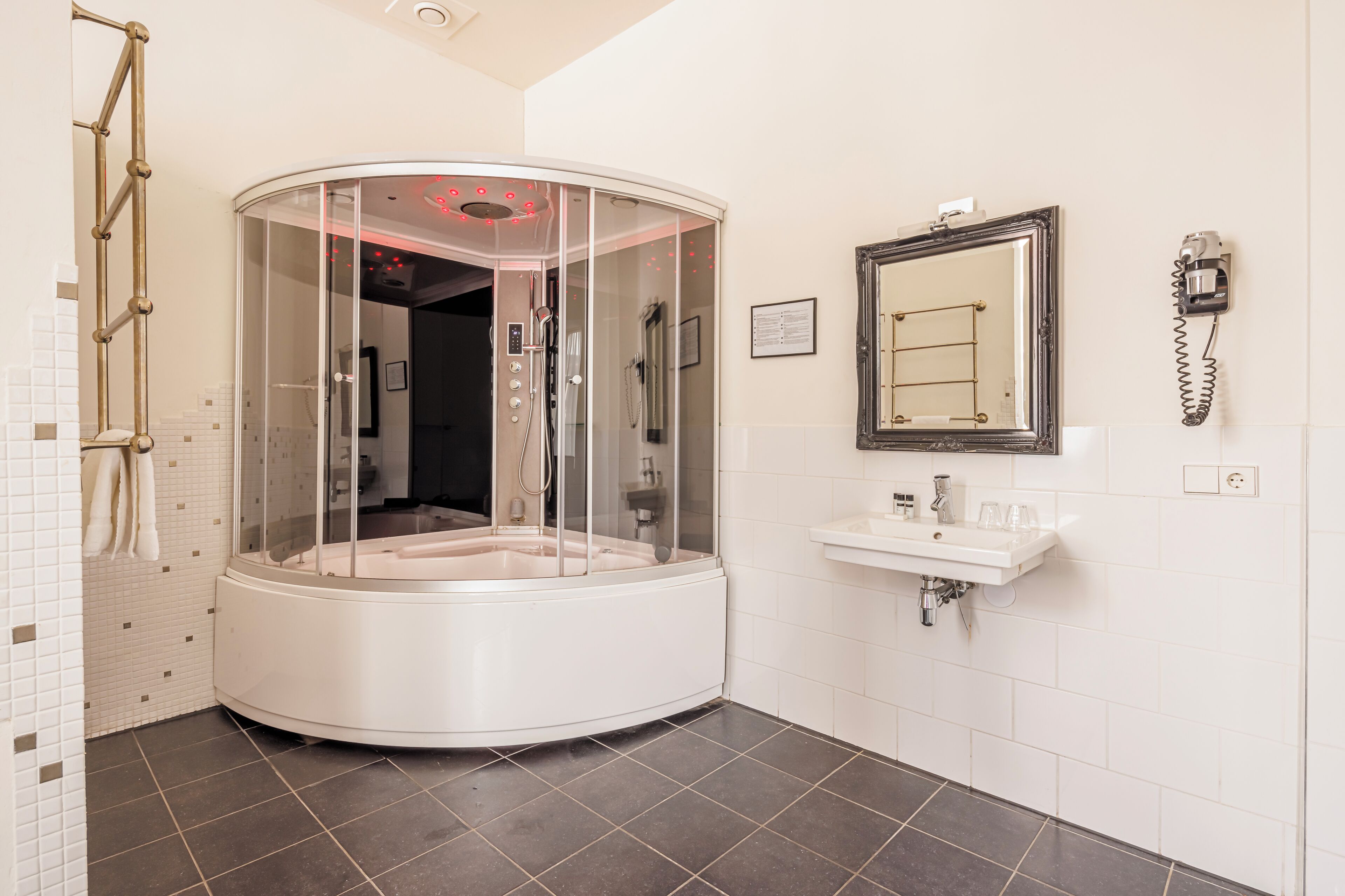 Un baño moderno con un jacuzzi con mampara de vidrio, un lavamanos y un espejo.