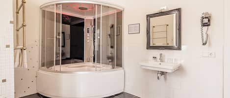 Un baño moderno con un jacuzzi con mampara de vidrio, un lavamanos y un espejo.